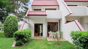 A two-story building with a red-tiled roof, a front door, and a small patio area with chairs and plants. - Wonderful  villa for 8 people with A/C, TV, terrace and pets allowed (San Michele Al Tagliamento)