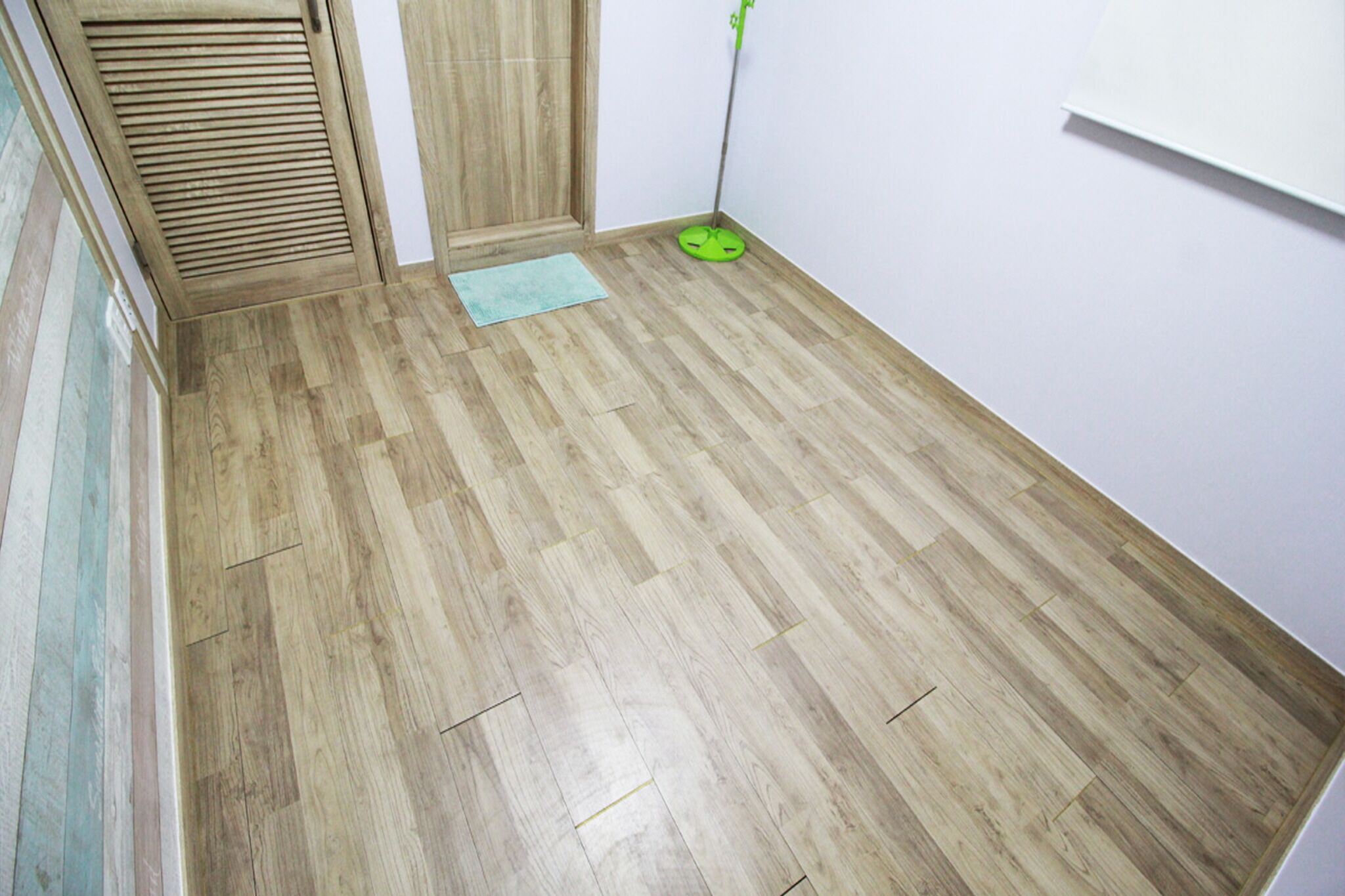 A room with wooden flooring, a green mat, and a green object on the floor.