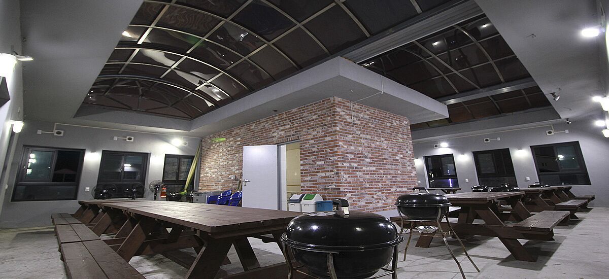 A modern indoor space with multiple picnic tables and a brick accent wall.