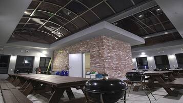 A modern indoor space with multiple picnic tables and a brick accent wall.