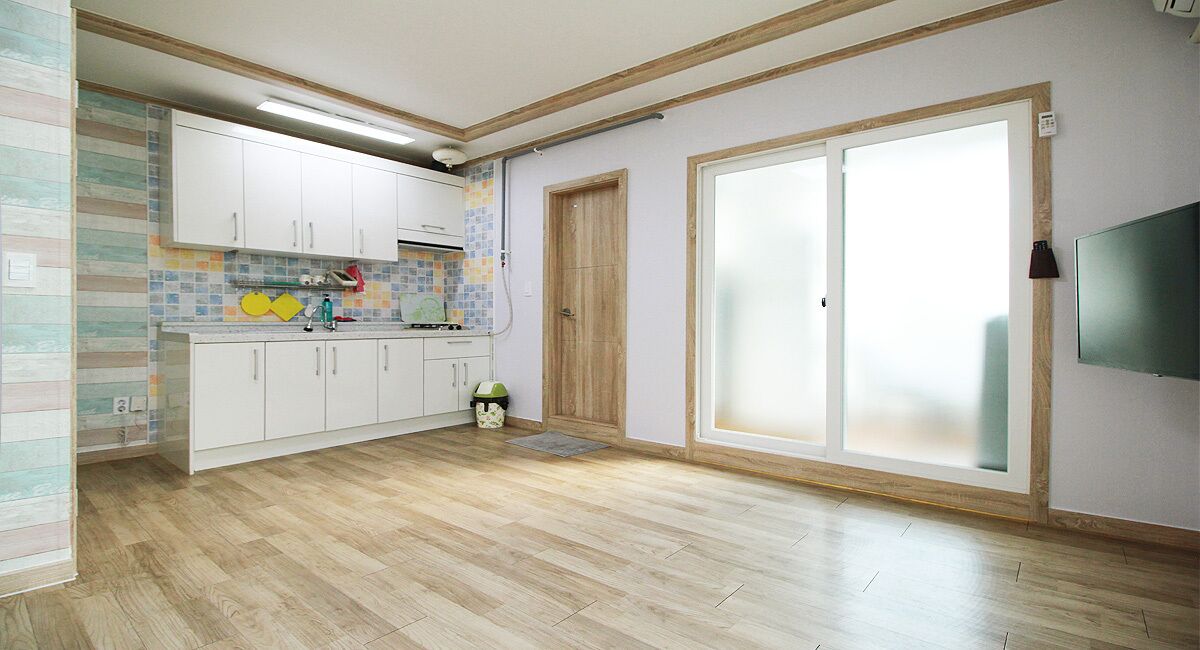 Een keuken met witte kasten, een betegelde achterwand en een houten vloer.