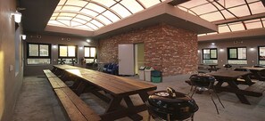 A covered outdoor dining area with brick walls, picnic tables, and barbecue grills. - Byeoldul Pension (Boryeong)