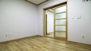 Una habitació amb terres de fusta, una porta corredissa de vidre i parets blanques.