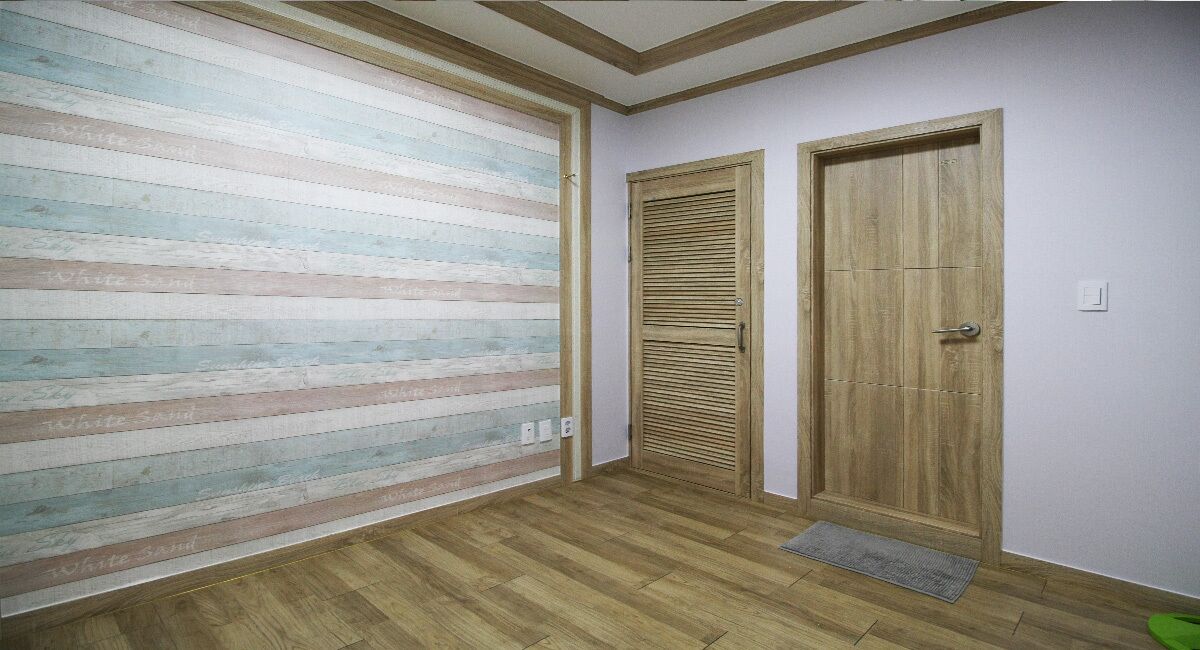 A hallway with a wooden floor, a striped wall, and two wooden doors.