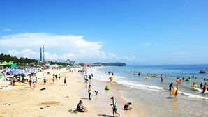 A beach with umbrellas, people, and water activities. - Byeoldul Pension (Boryeong)