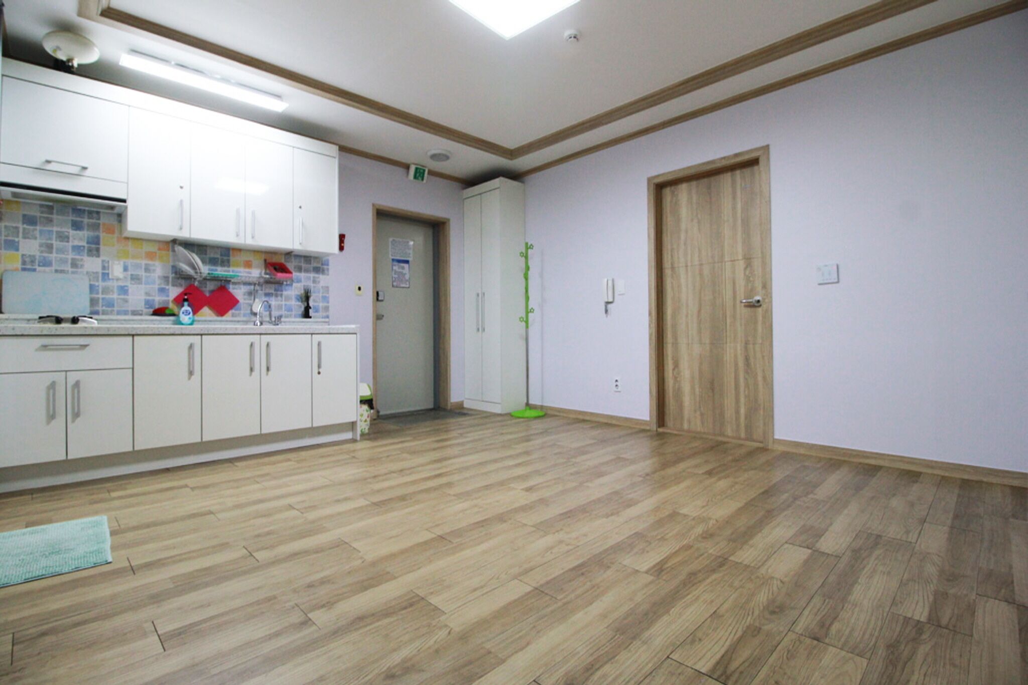 Una cocina amplia con piso de madera, gabinetes blancos y un tapete verde.