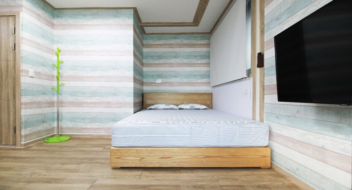 A bedroom with a wooden bed, striped wallpaper, and a large window.