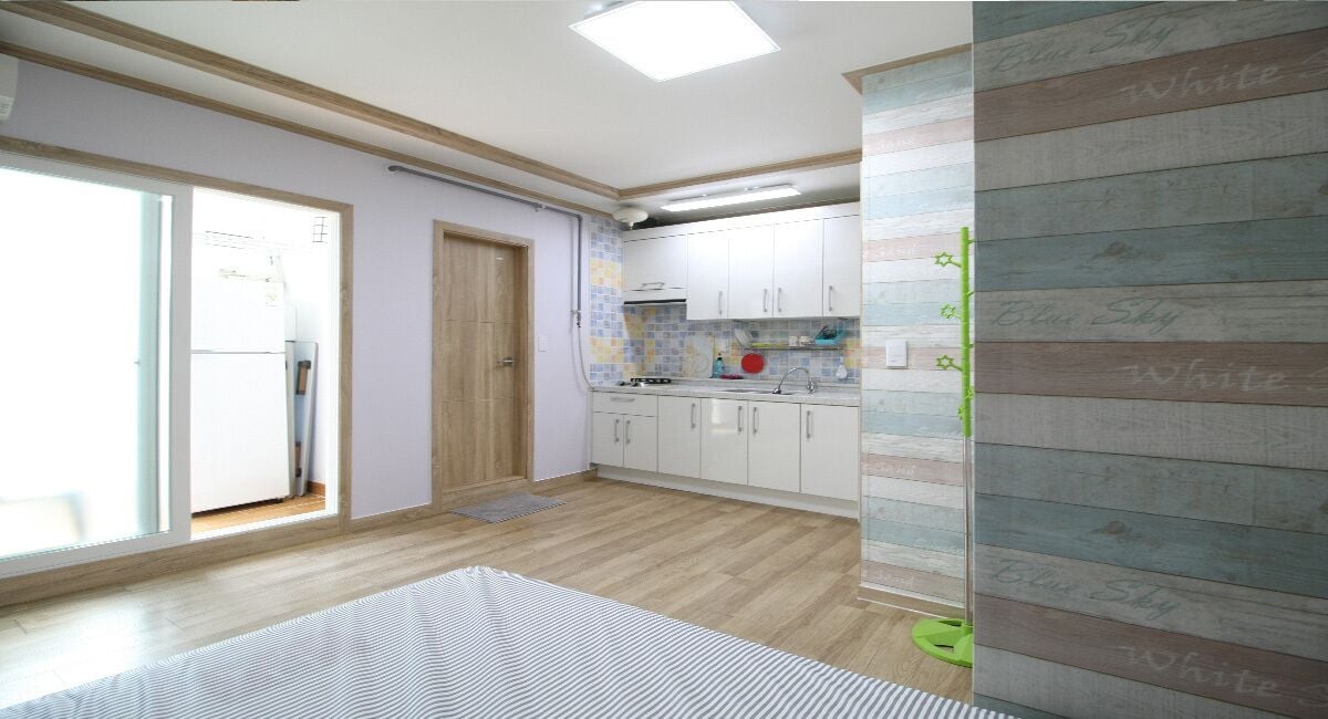 Una cocina con armarios blancos, suelo de madera y una ventana.