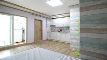 Una cocina con armarios blancos, suelo de madera y una ventana.
