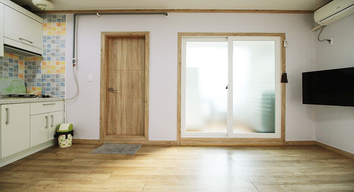 A kitchen with wooden cabinets, a tiled backsplash, a wooden door, and a sliding glass door.