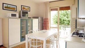 A compact kitchen with a dining area, a microwave, a refrigerator, and a gas stove. - Nice apartment for 5 guests with A/C, TV, balcony and pets allowed (Ca Grande Pineda)