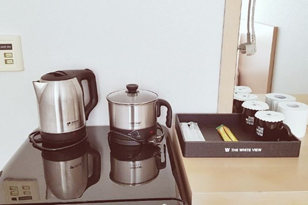 A coffee station with a kettle, a coffee pot, and a box of tea bags.