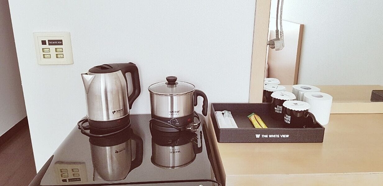 A kitchenette with a coffee maker, a pot, and a box of tea bags.