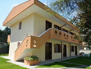 A two-story building with a beige facade, brown trim, and a small balcony.
