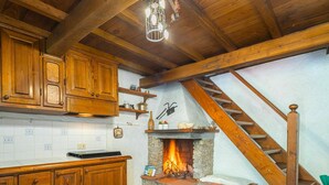 A rustic kitchen with wooden cabinets, a stone fireplace, and a wooden staircase. - Stunning private villa for 4 guests (Pontestazzemese)