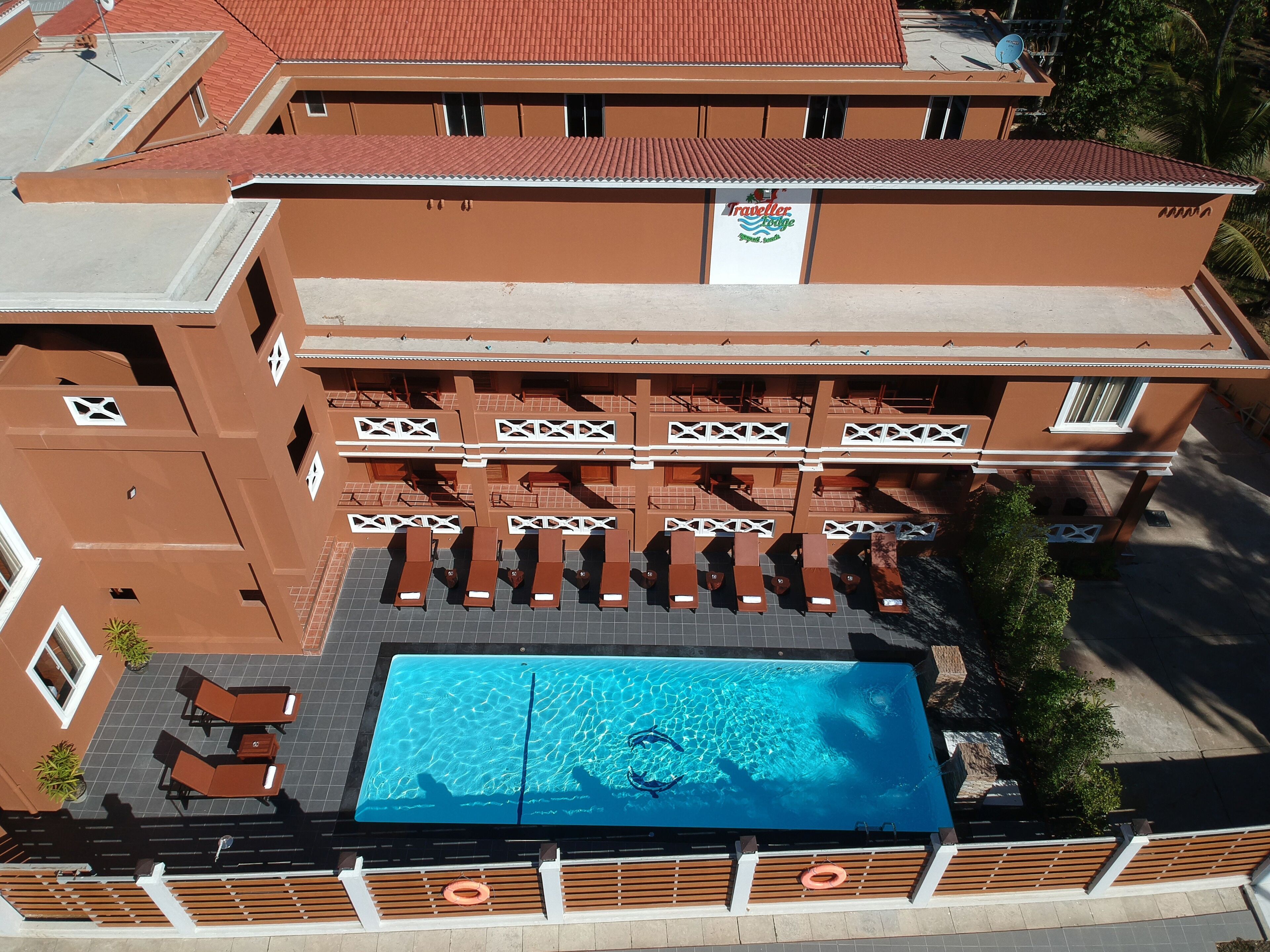 Un hotel con piscina en la azotea, varios balcones y un cartel que indica que es un 'Traveller's Lodge'.