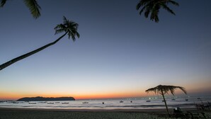A beach with palm trees, boats, and a sunset. - Traveller Lodge Ngapali by River Top - Hostel (Ngapali)