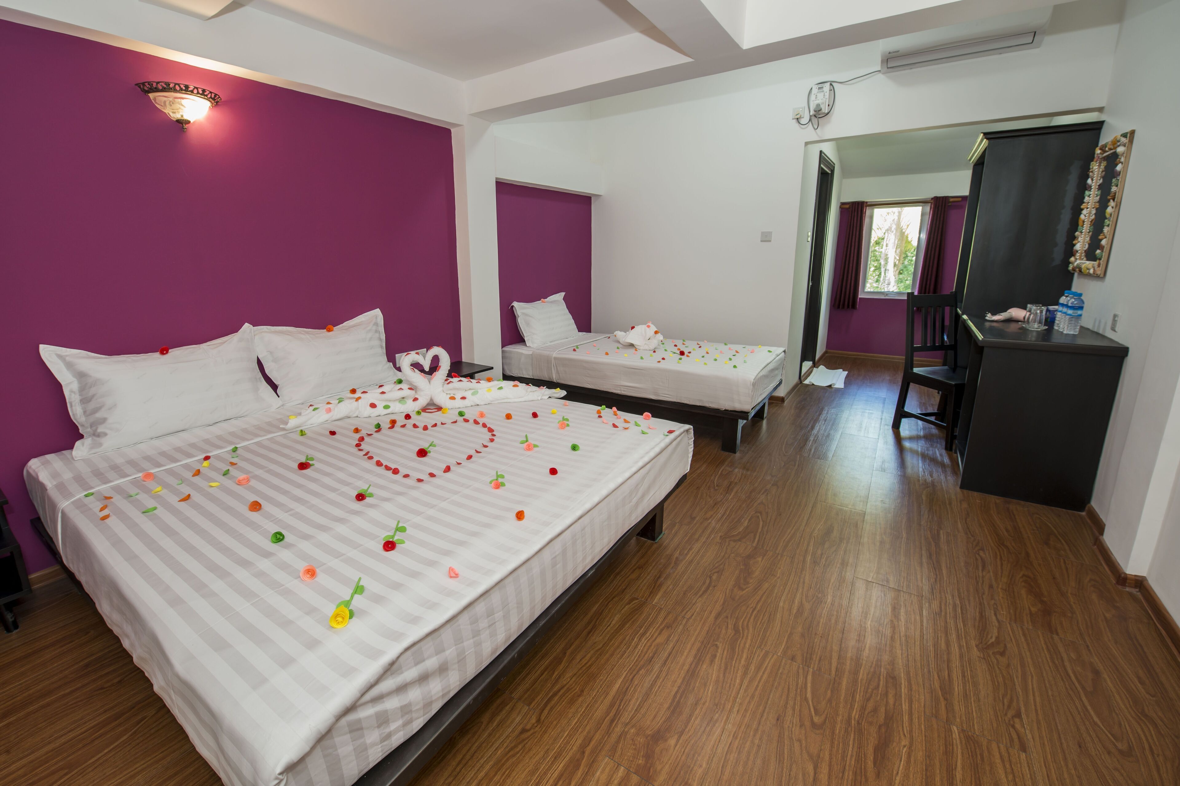 Habitación de hotel con dos camas, un escritorio y un espejo.