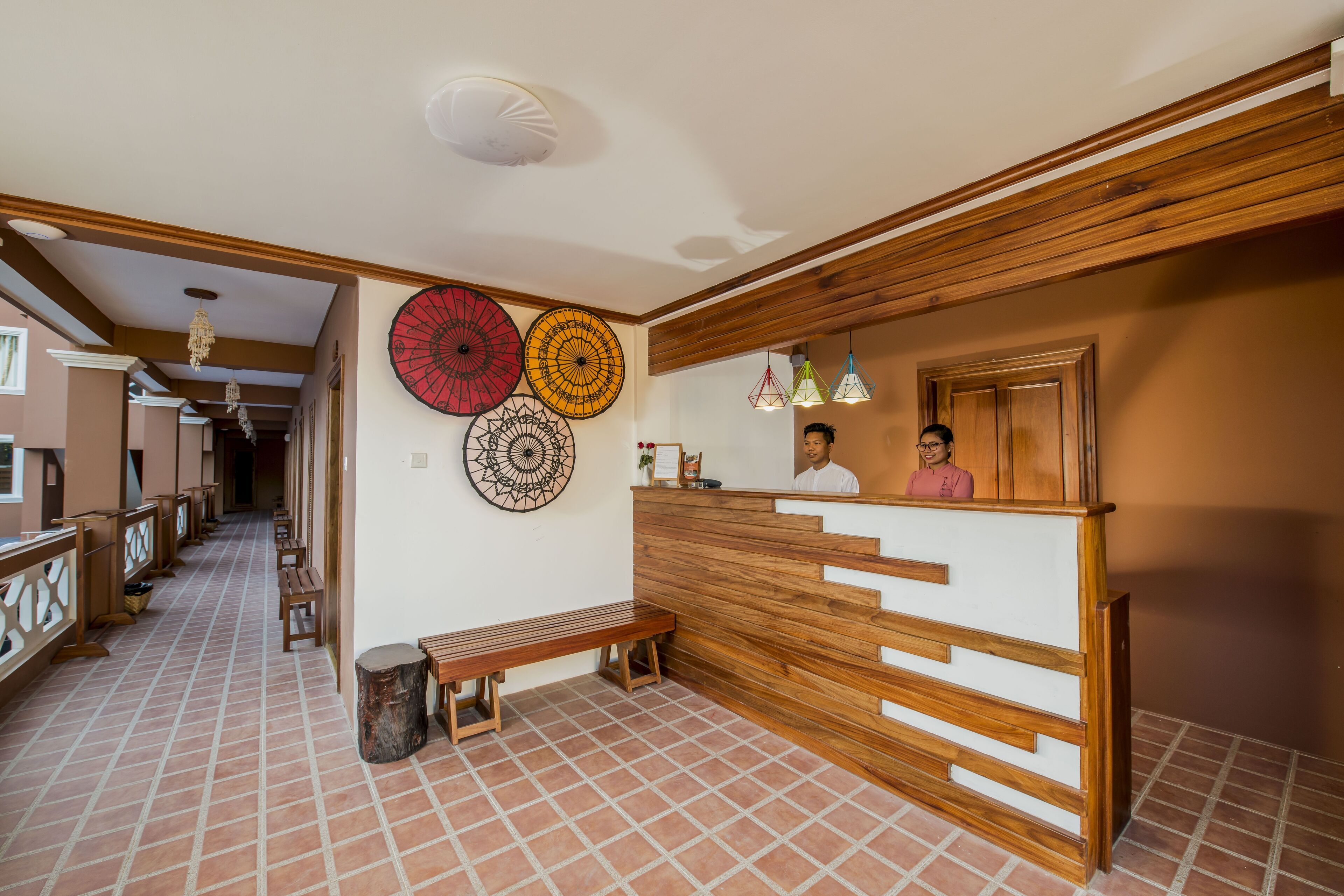 Un área de recepción con un mostrador de madera, un banco y piso de baldosas.