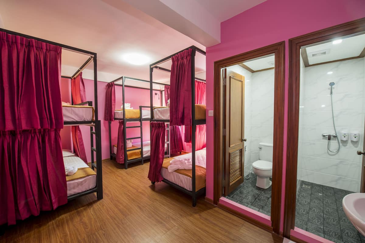 A room with bunk beds, a bathroom with a shower, and a sink.