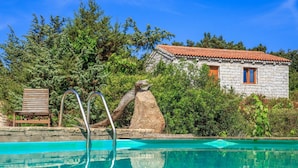 Ein Schwimmbecken mit einem Steinhaus im Hintergrund.