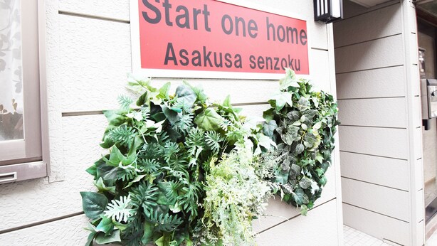 A sign reading "Start one home Asakusa senzoku" above a wall with a variety of green plants. - Start One Home Senzoku A (Tokyo)
