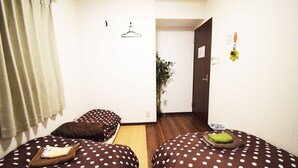 A room with two beds, a plant, and a door. - Start One Home Senzoku A (Tokyo)