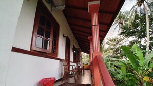 A covered porch with a tiled floor, wooden chairs, and a red trash bin. - Clara guest (Hikkaduwa)