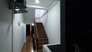 A narrow hallway with wooden flooring, a staircase leading to a loft area, and a skylight above. - Clara guest (Hikkaduwa)