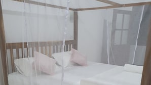 A bed with a mosquito net, a wooden headboard, and two pillows. - Clara guest (Hikkaduwa)