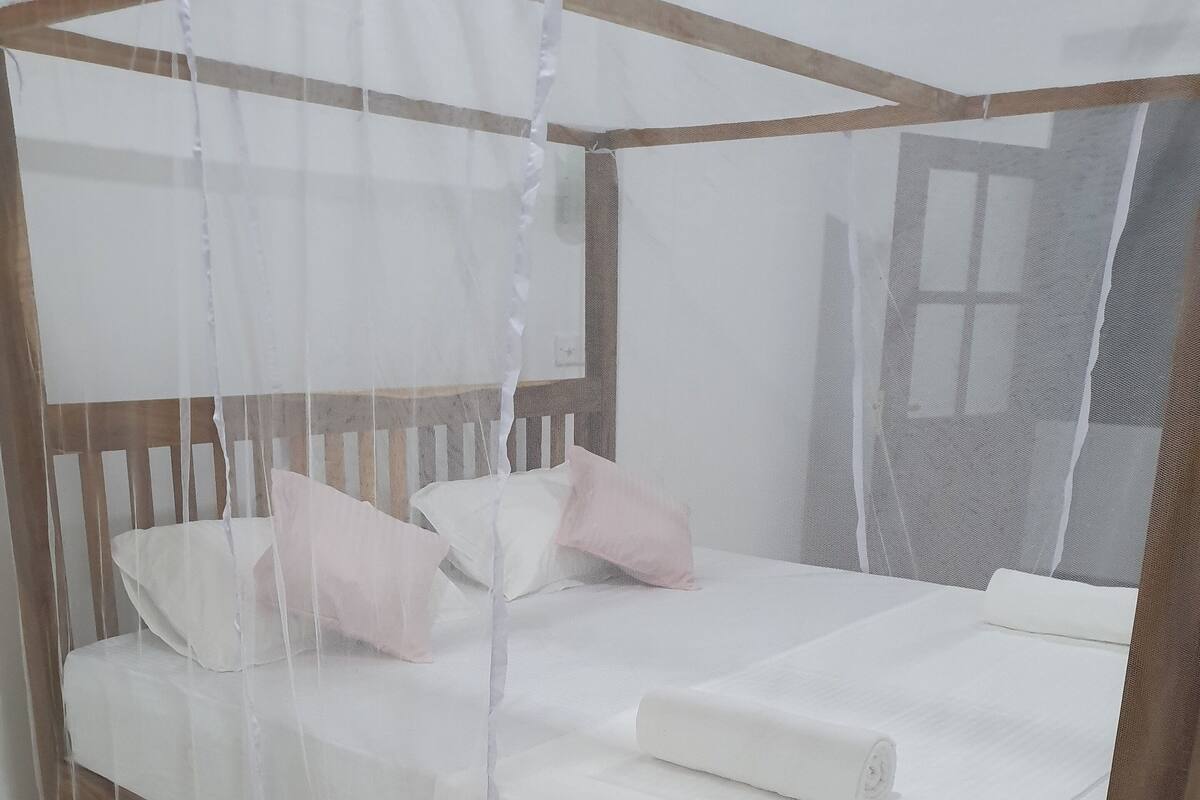 A bed with a mosquito net, a wooden headboard, and two pillows.