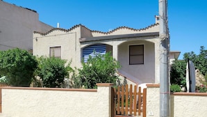 A house with a stucco exterior, a wooden gate, and a blue-striped window.
