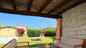 Eine Terrasse mit einem Holztisch, zwei Stühlen und einer Couch.