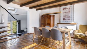 A dining area with a wooden table and chairs, a staircase, and a view of greenery. - Wonderful private villa for 5 people with WIFI, TV, terrace and pets allowed (Schoondijke)
