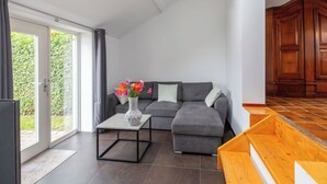 A modern living room with a grey sofa, a coffee table, and a wooden cabinet. - Wonderful private villa for 5 people with WIFI, TV, terrace and pets allowed (Schoondijke)