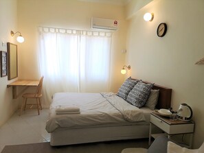A bedroom with a bed, bedside table, lamp, and a chair. - Aurora Court (George Town)