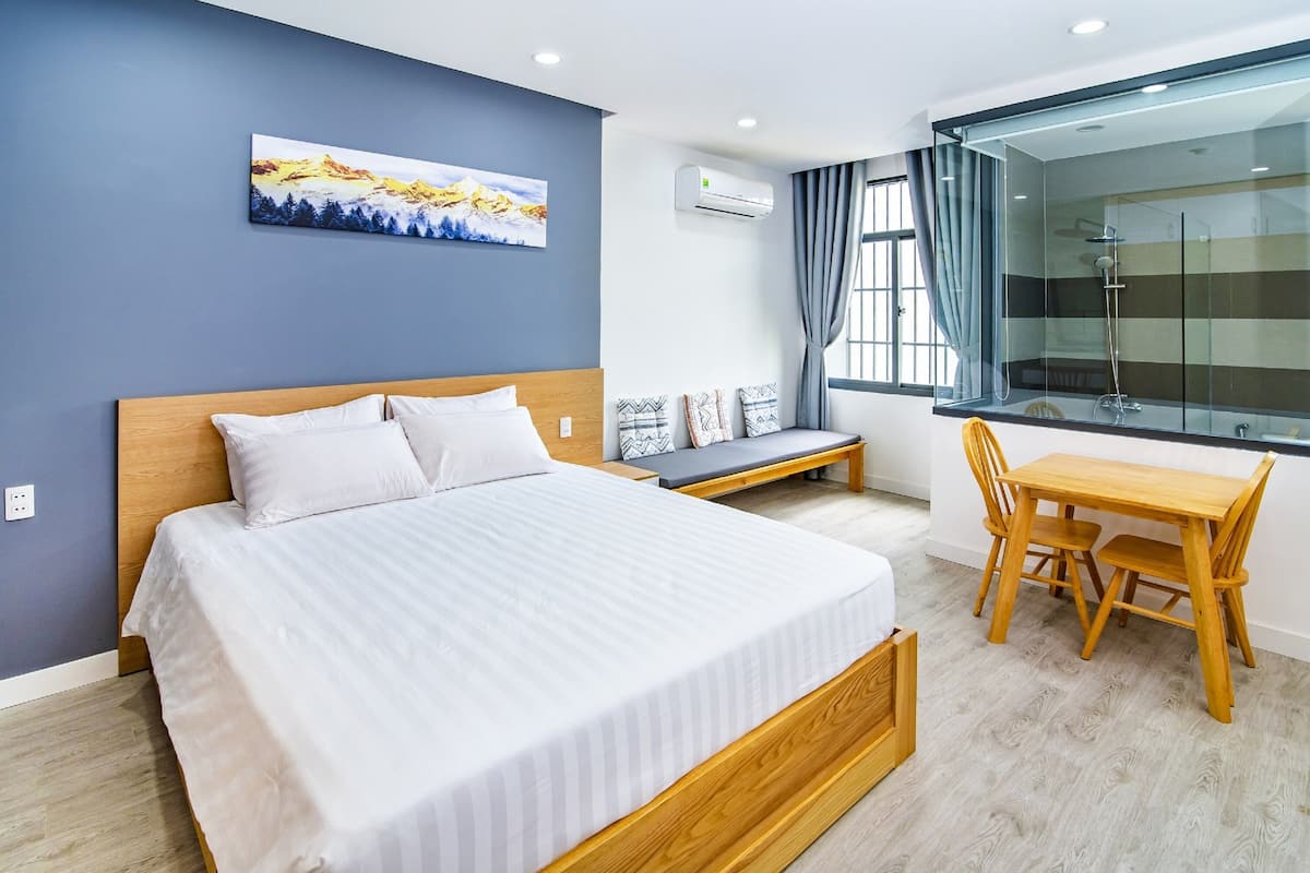 A modern hotel room with a large bed, a wooden desk, and a shower area.