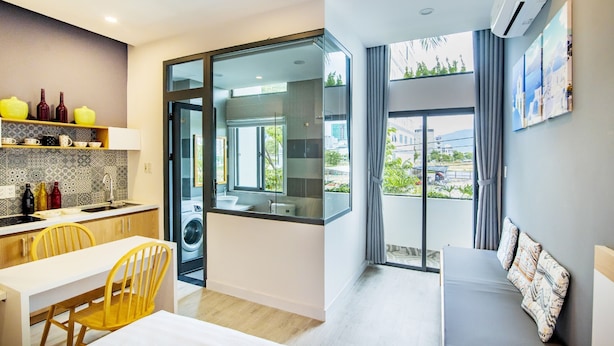 A modern kitchen with a dining area, a large window with a view, and a separate sleeping area with a view. - The Art - An Homestay (Da Nang)