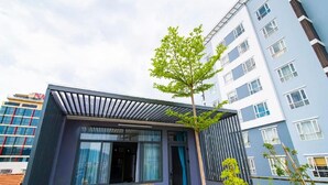 A modern building with a balcony, a tree, and a window with curtains. - The Art - An Homestay (Da Nang)