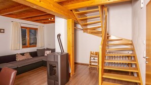 Ein gemütliches Wohnzimmer mit einer Holztreppe, einer Couch und einem Kaminofen.