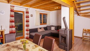 Ein gemütliches Wohnzimmer mit einer Couch, einem Esstisch und einem Kaminofen.