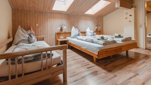 A cozy bedroom with wooden walls and a sloped ceiling, featuring two beds, a nightstand, and a skylight.
