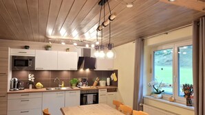A modern kitchen with wooden cabinets, a built-in oven, and a dining area with a wooden table and chairs.