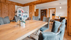 A spacious dining area with a wooden table and chairs, a kitchen in the background, and a wooden ceiling. - Beautiful  villa for 16 guests with WIFI, TV and terrace (Piesendorf)
