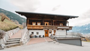 A wooden chalet with a balcony, stone steps, and a view of mountains. - Beautiful  villa for 16 guests with WIFI, TV and terrace (Piesendorf)