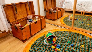 Una habitación con baúles de madera, una alfombra estampada y un espejo que refleja el ambiente.