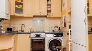 Una cocina compacta con armarios color beige, lavadora, estufa y refrigerador.