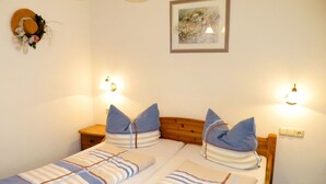 A double bed with striped bedding, two pillows, a wooden headboard, bedside tables, wall-mounted lamps, and a framed picture on the wall.