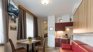 A compact living space with a kitchenette, a dining area, and a red sofa. - Beautiful apartment for 4 people with WIFI, pool, TV, balcony and pets allowed (Stumm)