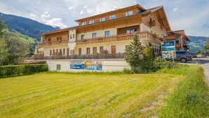 Een meerlaags hotel met balkons, een bord dat appartementen adverteert, en een uitzicht op bergen op de achtergrond.